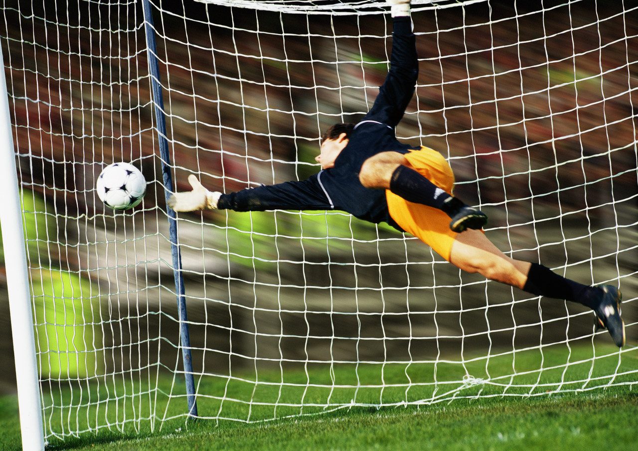 Torwart hechtet vor dem Tornetz nach dem Ball